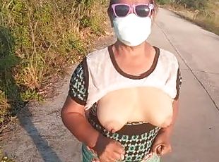 Auntie walks and shows off her breasts on the side of the road.