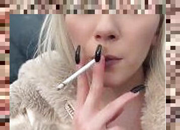 A glamour teen is smoking and spitting loogies on the ground making big spit puddle