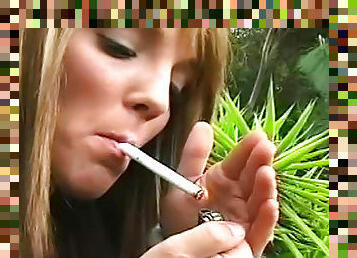 Cute blonde is smoking a cigarette in the garden