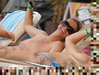 Tattooed girl and her topless friend tanning topless